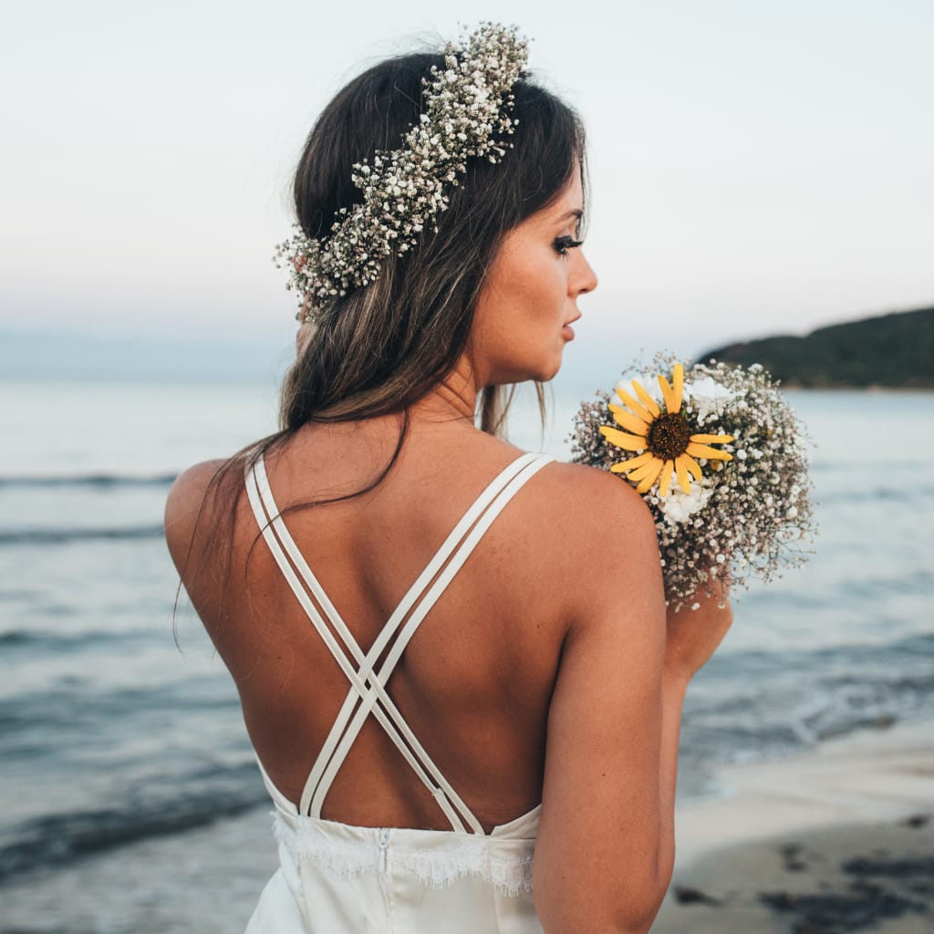wedding hair long wave wearing boho wedding flower crown holding wedding sunflowers at beach back view of bride