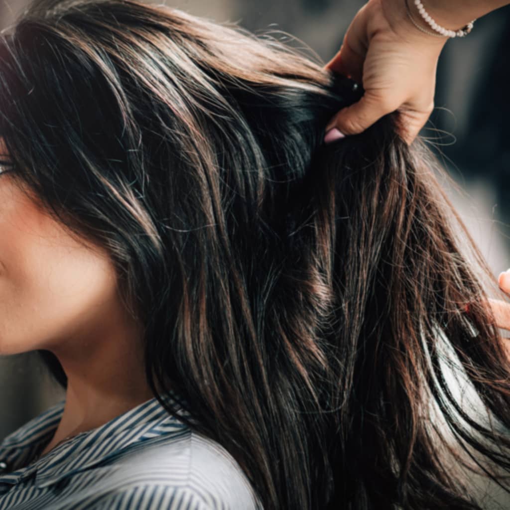 long thick hair brunette held up by mobile hairdresser hand