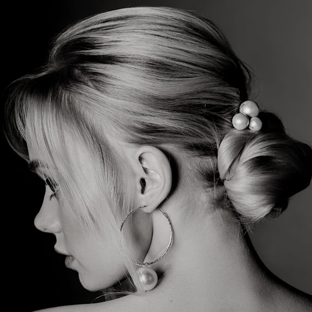 wedding hair bridal styled with low bun and pearl wedding hair accessories looking to the side