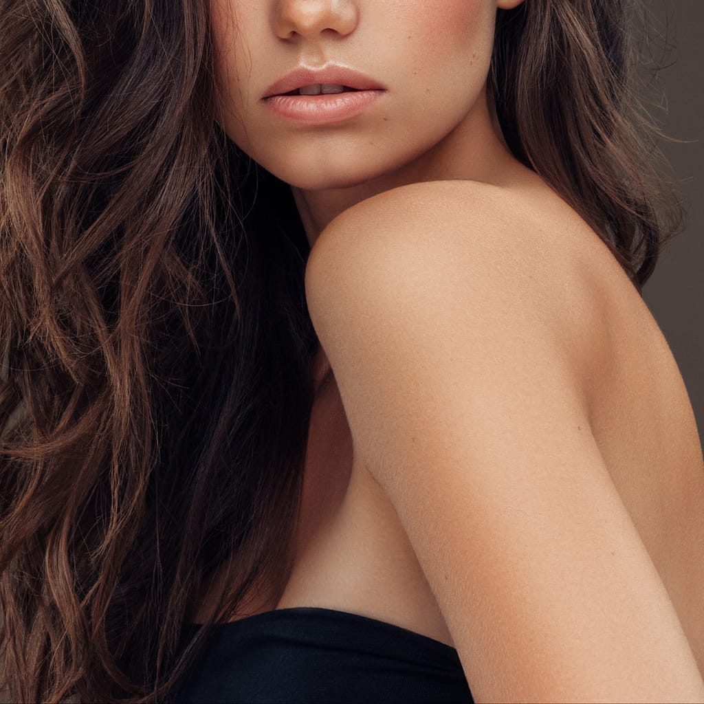 loose wavy brunette hair close up of model face, shoulder, arm and hair