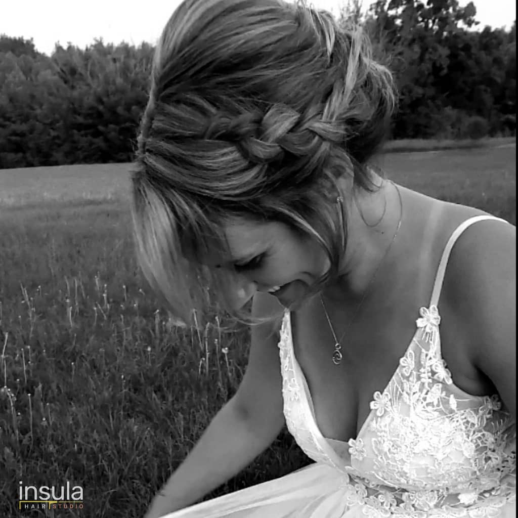 short hair bride with wedding hairstyle low updo with braid bride smiling in field in wedding dress