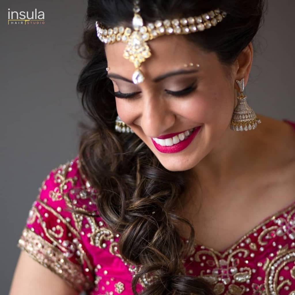 bridal hair updo long wedding braid south Asian bride wearing wedding hair accessories smiling looking down