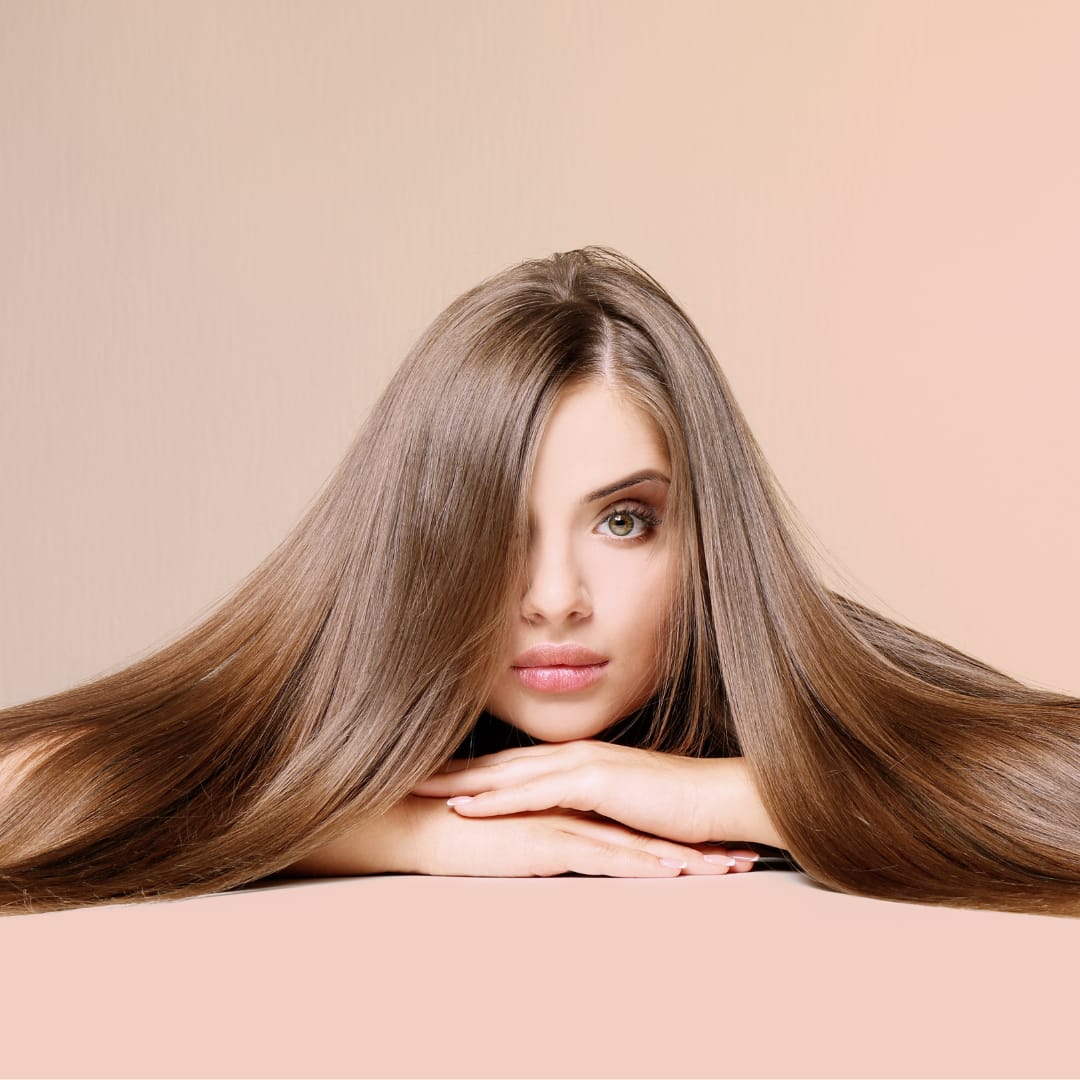 a woman is resting her head on her hands with long hair extensions laid out over top of her arms