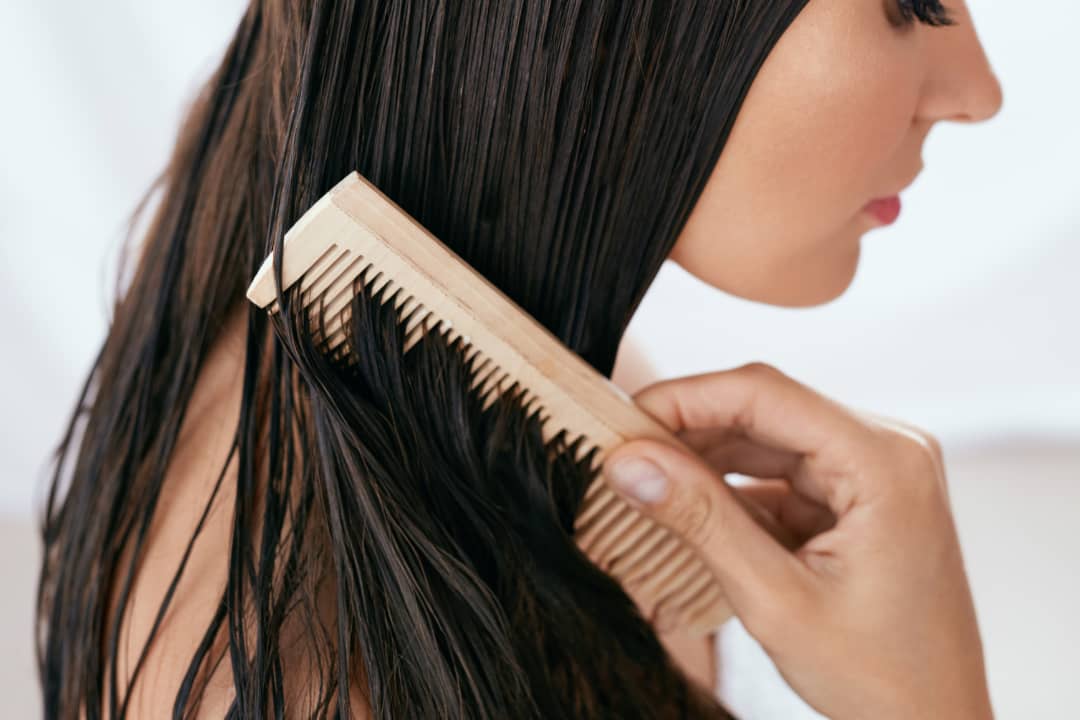 brunette woman combing a hair mask through her hair