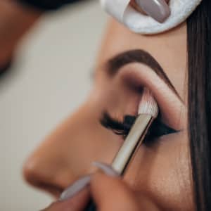 wedding make up artist applying makeup to bride wearing bridal false lashes close up of bride eye