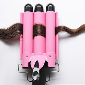 Pink hair crimper tool in action, crimping a section of dark brown hair for a wavy style